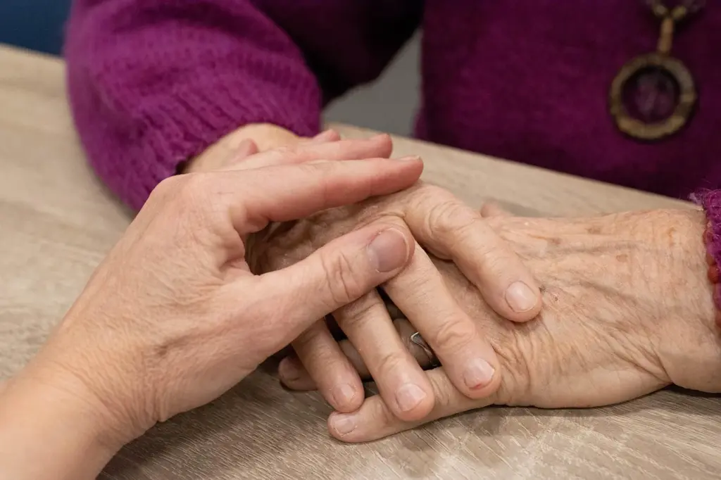 Eine Hand liegt tröstend auf der Hand einer älteren Person